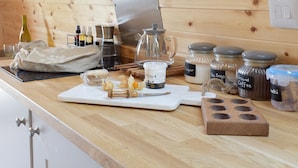 A kitchen counter with various food items and kitchenware, including jars labeled 'Sugar', 'Tea Bags', and 'Ground Coffee', a coffee maker, and a cutting board with food items. - Peace and quiet, sat in the middle of your own field with a private hot tub. (Leadburn, near West Linton)