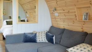 A cozy room with a grey sectional sofa, a large mirror, and wooden paneling on the walls. - Peace and quiet, sat in the middle of your own field with a private hot tub. (Leadburn, near West Linton)