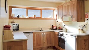 A kitchen with wooden cabinets, a dishwasher, a stove, and a window above the sink. - A beautiful barn conversion set within the grounds of a working farm. (Benmore near Dunoon)