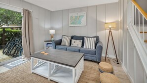 Un salon moderne avec un canapé gris, une table basse, un lampadaire et une carte accrochée au mur.