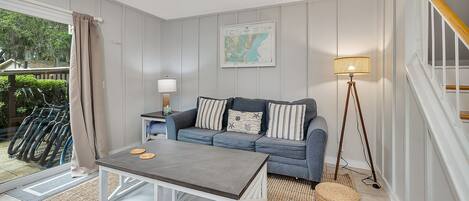 A modern living room with a grey sofa, a coffee table, a floor lamp, and a map on the wall.