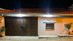 Um edifício com uma grande porta de madeira, uma pequena janela e um telhado em telhas.