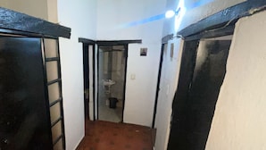 Um corredor estreito com piso de azulejos e portas emolduradas a preto em ambos os lados.