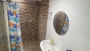 Casa de banho com chuveiro, pia e espelho.