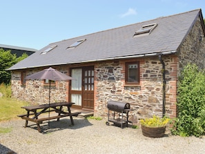 A stone building with a sloped roof, a wooden door, and a window. - 3 bedroom accommodation in Dunterton, near Tavistock (Dunterton, near Tavistock)