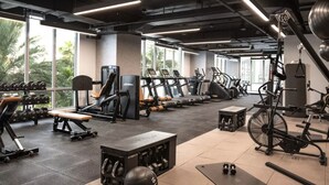 Un gimnasio con diverso equipo de ejercicio, incluyendo cintas de correr, máquinas de pesas y pesas libres.