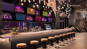 Zona de bar moderna con una barra larga, varios taburetes y una amplia variedad de botellas en estanterías.