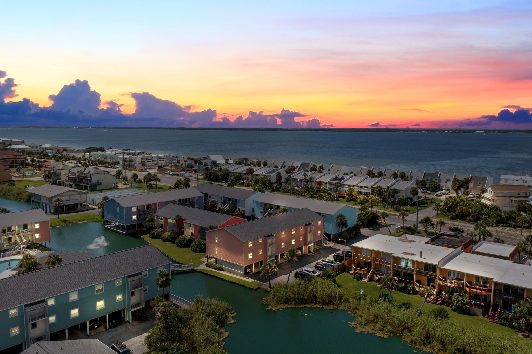 A resort with multiple buildings, a marina, and a sunset view.