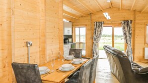 A wooden interior with a dining table set for four, a sofa, and a kitchen area visible through an open door. - 2 bedroom accommodation in LLANFAIRPWLLGWYNGYLL (LLANFAIRPWLLGWYNGYLL)