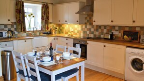 Una cocina con una mesa de comedor preparada para cuatro personas, una lavadora y un salpicadero de azulejos.