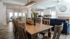 Un comedor espacioso con una mesa y sillas de madera, una lámpara colgante y un sofá azul al fondo.