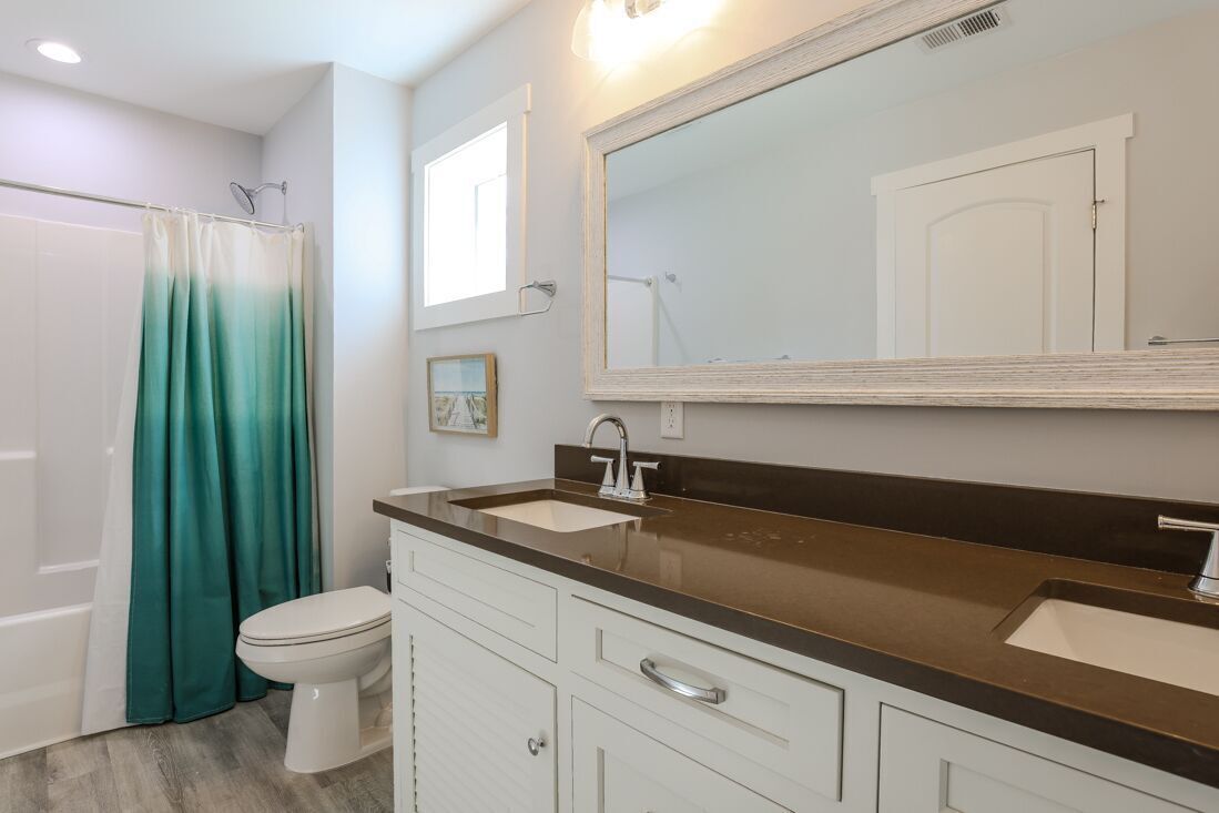 Une salle de bain comprenant une douche, des toilettes, un meuble-lavabo avec un miroir et un évier.