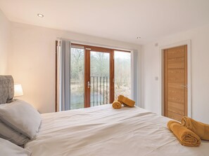 Ein Schlafzimmer mit einem Bett, einem Fenster mit Vorhängen, einer Tür und einer Lampe.