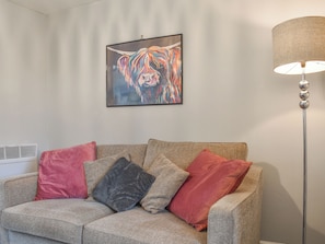 A living room with a sofa, pillows, a framed artwork, and a floor lamp.