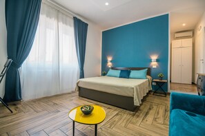 Ein Schlafzimmer mit einem Bett, einem kleinen Tisch mit einer Schale, einer blauen Wand und einem Kleiderschrank.