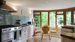 A modern kitchen with wooden cabinets, a gas stove, and a window overlooking greenery.