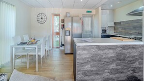 A modern kitchen with a central island, a dining area with white chairs, and a refrigerator. - 1 Ladyknowe - UK39970 (Moffat)