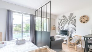 Une chambre d’hôtel moderne équipée d’un lit, d’un bureau, d’une chaise, d’une télévision et d’une grande fenêtre avec des rideaux.