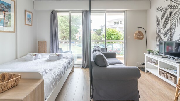 Une chambre d’hôtel moderne équipée d’un lit, d’un canapé, d’une télévision et d’un balcon offrant une vue sur la ville.
