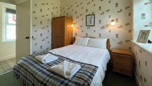 A bedroom with a bed, a wardrobe, a nightstand, and a wall-mounted light fixture. - Birch Cottage - UK38992 (Dalcross)