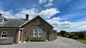 A stone house with a sloped roof, a chimney, and a gravel driveway. - Birch Cottage - UK38992 (Dalcross)