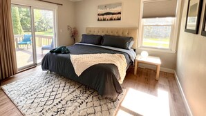 Een slaapkamer met een groot bed, een plafondventilator, een raam met jaloezieën en uitzicht op de omgeving.