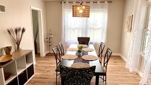 Een eethoek met een houten tafel, zwarte stoelen en een hanglamp.
