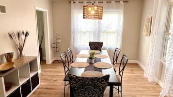 Un espace repas avec une table en bois, des chaises noires et un luminaire suspendu.