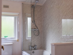 Un baño con ducha de vidrio, bañera y retrete.