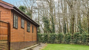 A wooden cabin with a sloped roof, a gravel pathway leading to the entrance, and a grassy yard. - 4 bedroom accommodation in Truro (Truro)