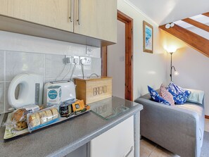 A kitchen with a coffee maker, toaster, and bread box, a couch with pillows, and a framed picture on the wall.