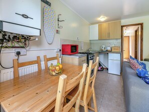 A compact kitchen with a dining table, chairs, a microwave, a stove, and a refrigerator.