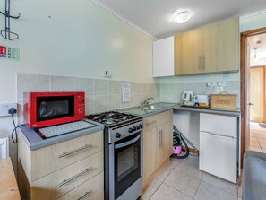 Una cocina compacta con estufa a gas, horno, microondas y una panera sobre la encimera.