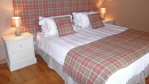 A bedroom with a plaid headboard, white bedding, and two bedside lamps.
