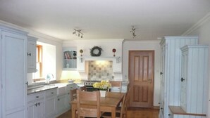 A kitchen with white cabinets, a wooden dining table, and a stove.