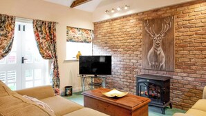 A cozy living room with a brick wall, a fireplace, a television, and a sofa.