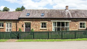 A brick building with a sloped roof, a wooden fence, and a clear sky.
