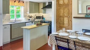 A compact kitchen with a central island, a dining table set for four, and a wooden door.