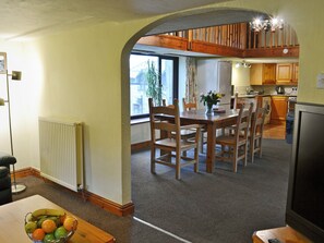 A dining area with a wooden table and chairs, a fruit bowl, and a view through an archway to a kitchen and living space. - 3 bedroom accommodation in Dunterton, near Tavistock (Dunterton, near Tavistock)