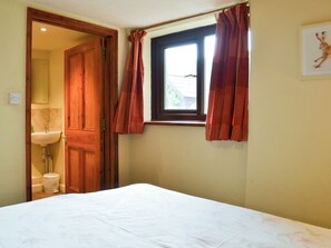 A bedroom with a bed, a window with curtains, a sink, and a door leading to a bathroom. - 3 bedroom accommodation in Dunterton, near Tavistock (Dunterton, near Tavistock)