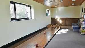 Una habitación con piso de madera, un sofá, una estantería y una ventana con vistas a árboles.