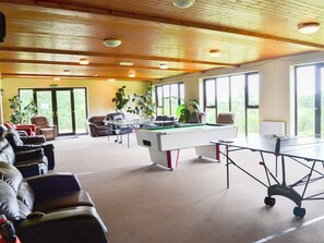 A billiards room with a pool table, leather chairs, and large windows.