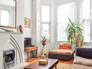 A living room with a fireplace, a television, a sofa, and a large window with blinds. - 5 bedroom accommodation in Anfield, near Liverpool (Anfield, near Liverpool)