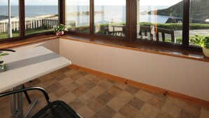 Ein Zimmer mit Meerblick, ein Tisch, ein Stuhl und eine Topfpflanze.