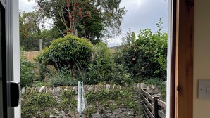 A garden with a gravel path, a wooden fence, and various plants and trees. - Detached cottage on the banks of Loch Long and the Firth of Clyde near Dunoon. (Ardentinny, Dunoon)
