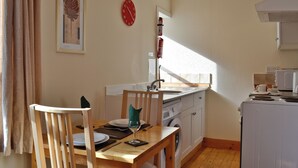 A small kitchen with a wooden table, chairs, a sink, and a washing machine. - Detached cottage on the banks of Loch Long and the Firth of Clyde near Dunoon. (Ardentinny, Dunoon)