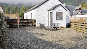 A white building with a sign reading "Sanna" in front of a gravel driveway. - Detached cottage on the banks of Loch Long and the Firth of Clyde near Dunoon. (Ardentinny, Dunoon)
