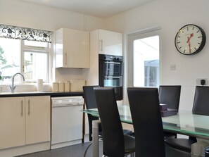 Una cocina moderna con armarios blancos, una mesa de comedor de vidrio y un horno negro.
