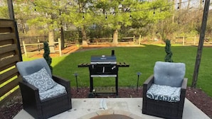 An outdoor patio area with two wicker chairs, a small grill, and a manhole cover. - Newly renovated 1400 Square Foot 3 Bedroom Home. (Indianapolis,)