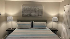 A bedroom with a bed, two bedside tables, two lamps, and a painting on the wall. - Newly renovated 1400 Square Foot 3 Bedroom Home. (Indianapolis,)